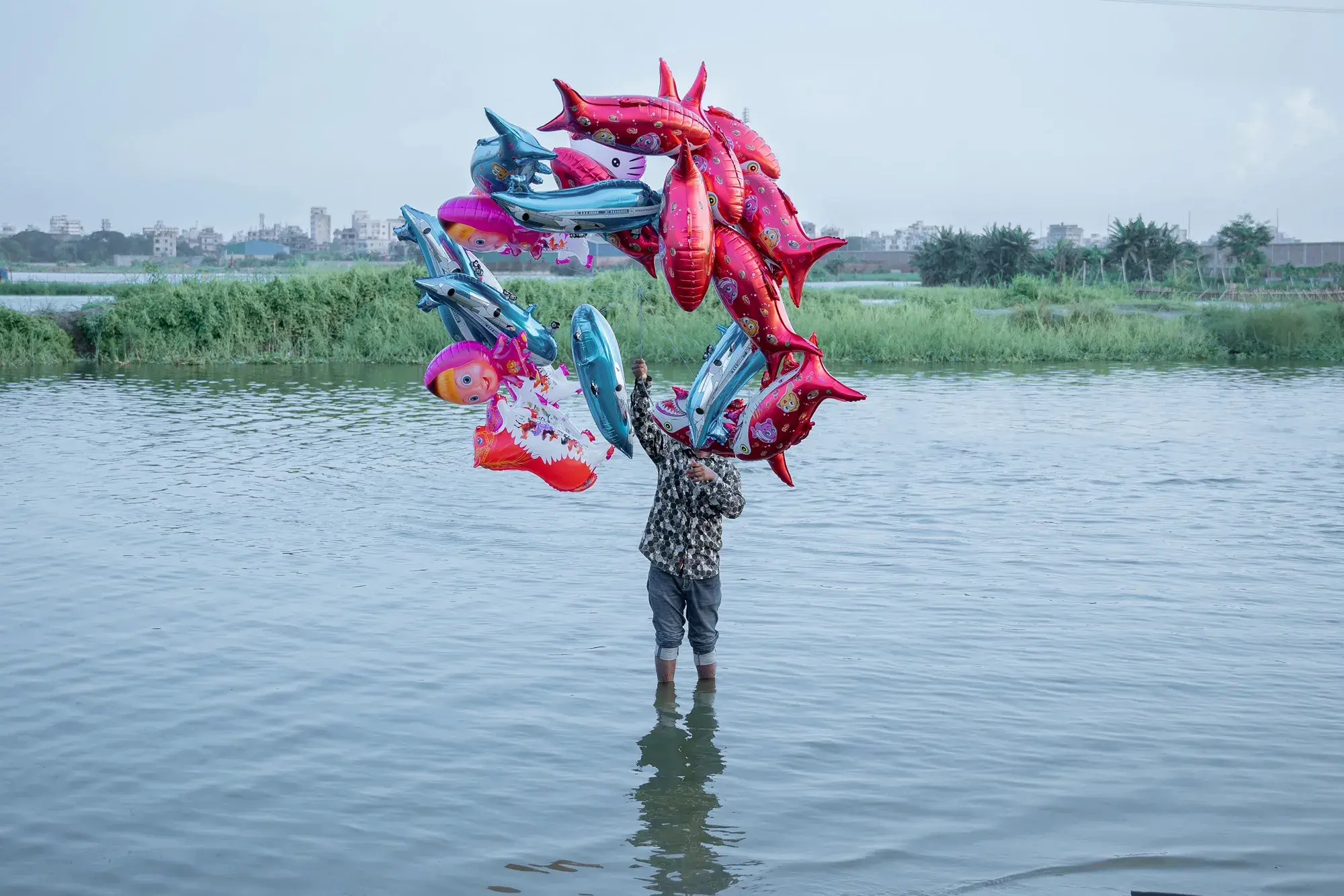 man holds fish balloons in river