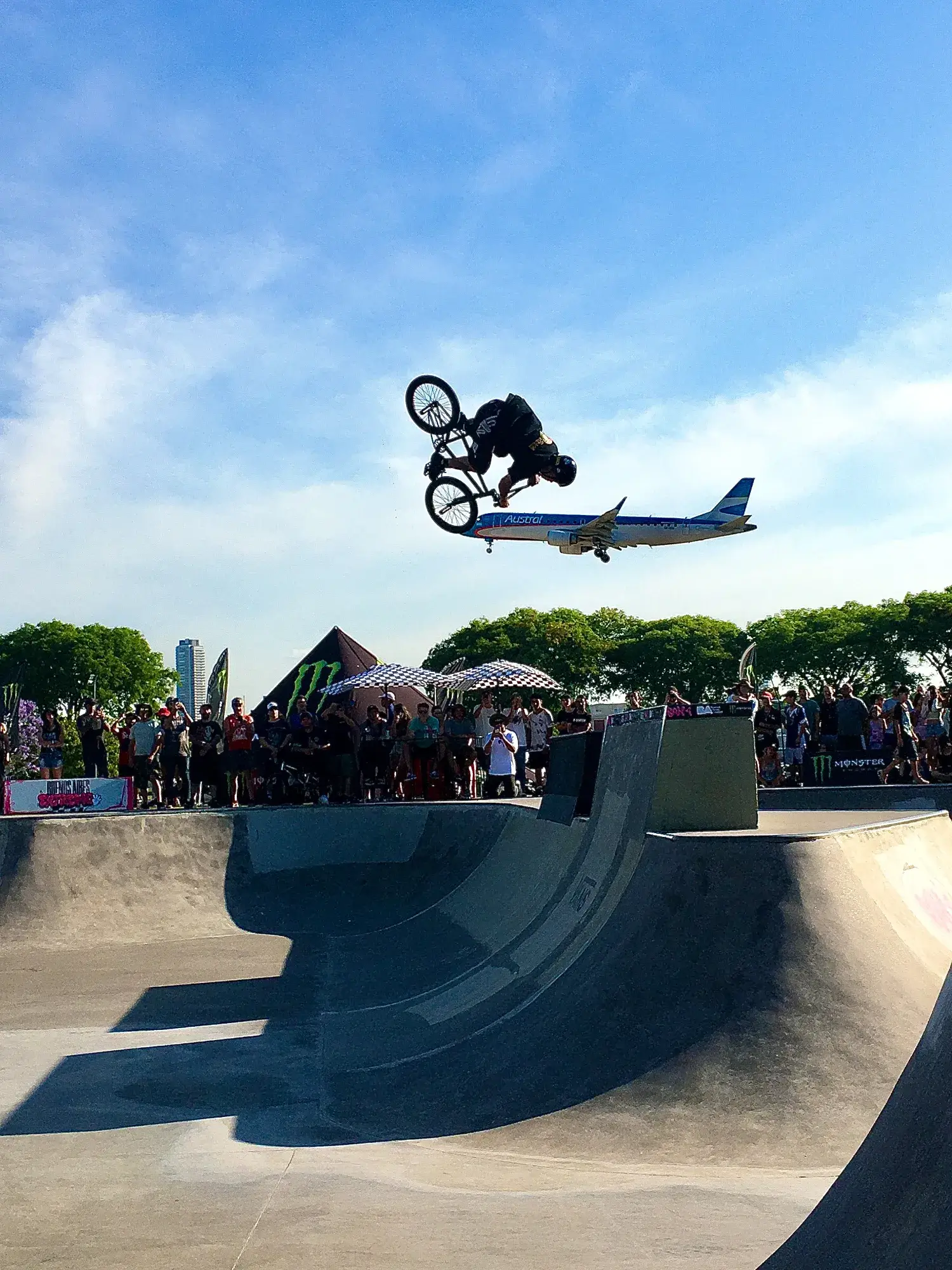 a bmx rider performing a backflip; simultaneously capturing the landing of a plane behind them, giving the illusion of a plane propelling the rider forward. 