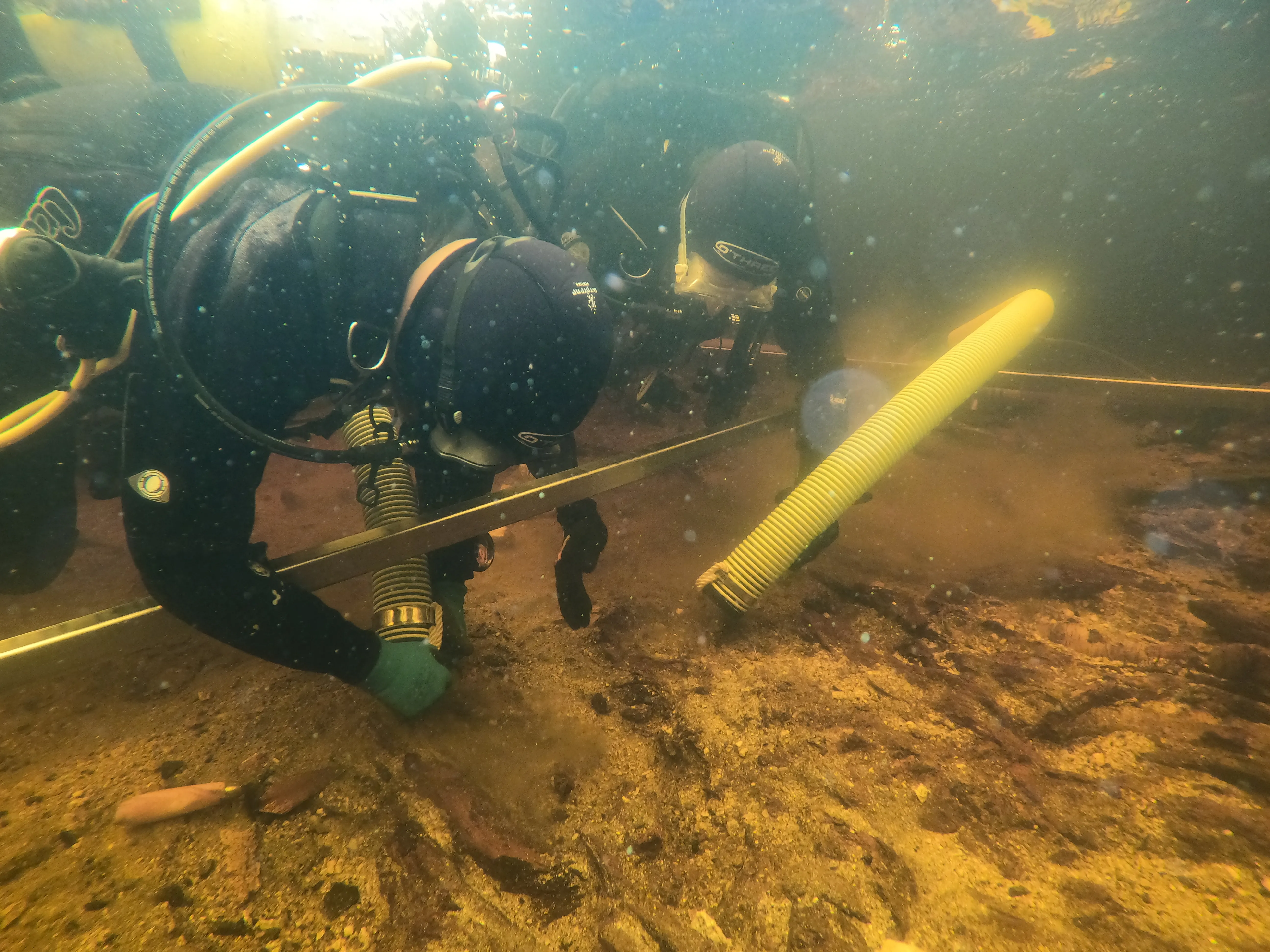 two divers in full gear examining and under water dig site in a scottish lake